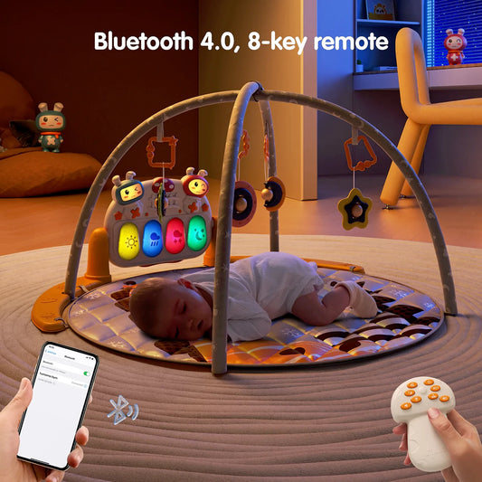 A baby play gym shown in a cozy, dimly lit room. A baby is sleeping on the soft, patterned play mat under the gray arches that hold hanging toys. At the back of the gym, a light-up music and activity panel with colorful glowing buttons is visible. A hand holds a smartphone displaying Bluetooth connectivity, while another hand holds an 8-key remote control, highlighting the gym’s Bluetooth 4.0 and remote-control features.