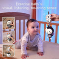 A baby staring at a plush hanging rattle bee baby toy
