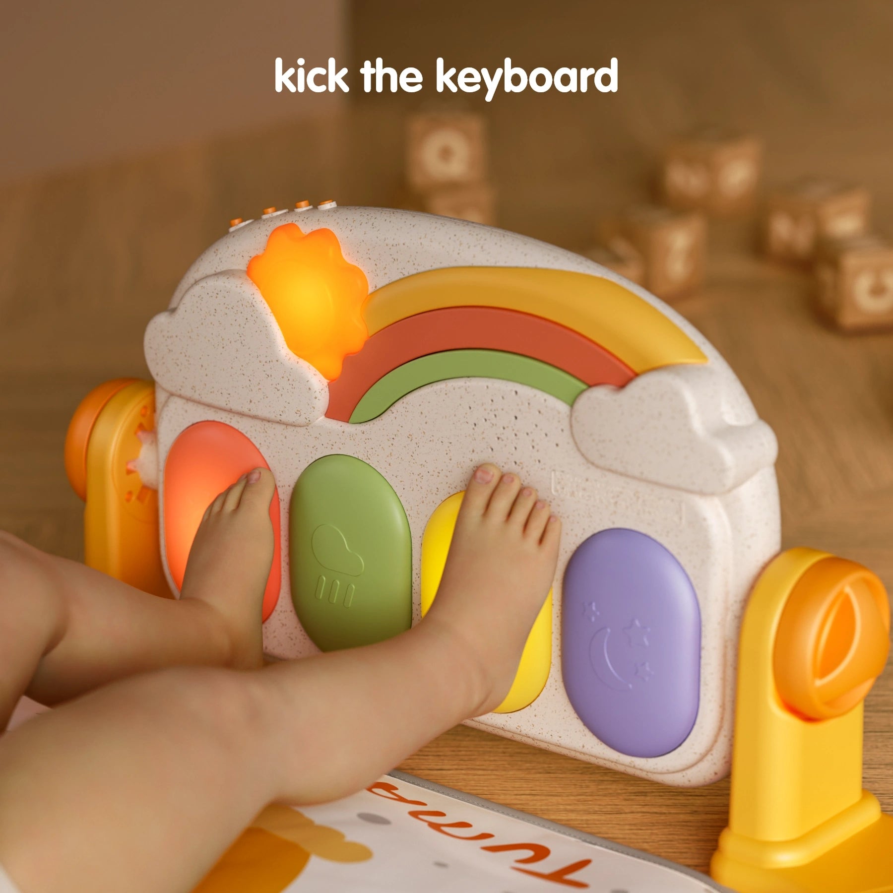 Baby kicking Tumama rainbow piano keyboard on play gym, colorful keys with breathing light feature encouraging interactive foot play.