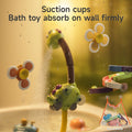 A dinosaur-themed bath toy is attached to a bathtub wall using multiple suction cups, with water spraying from its mouth. Flower-shaped suction cup toys and a colorful spiral track are also secured to the wall. Floating toys are visible in the tub, and a mesh storage bag with bath toys appears in the corner. The text reads, 