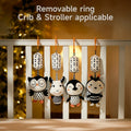 Plush tambourine cow owl penguin and bee black white toys are hanging on the crib