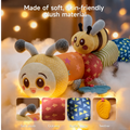 Soft plush caterpillar toy featuring colorful segments, a smiling face, and a bee companion; surrounded by warm lighting, highlighting its textures including rustle paper, teether, and soft fabric for tactile exploration.
