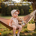 A toddler sits on a hammock outdoors, holding a soft teddy bear and owl plush toy. The scene highlights the toy’s skin-friendly short plush fabric, with a close-up texture swatch shown in the corner.