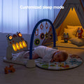 Baby sleeping on a play mat with a blue arch and hanging rattles, while the musical keyboard toy is glowing in customized sleep mode with warm yellow lights in a darkened room.