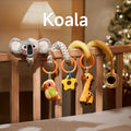 A koala-themed spiral baby toy attached to a crib, featuring a plush koala, parrot, star-shaped teether, giraffe, and bead rattle. The toy is designed to provide interactive fun and promote sensory development for babies.