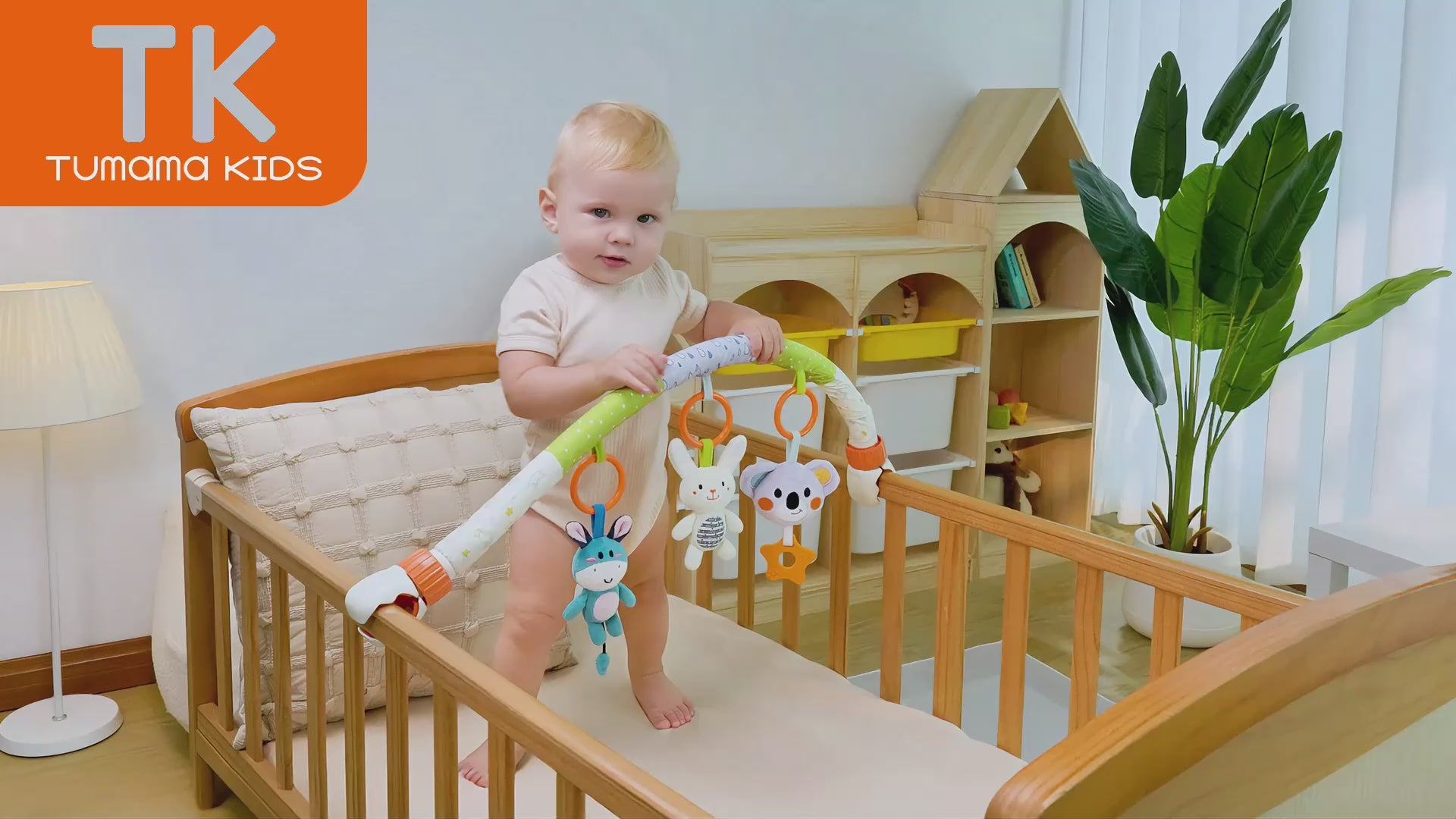 Video shows baby in crib interacting with stroller arch toy plush toy